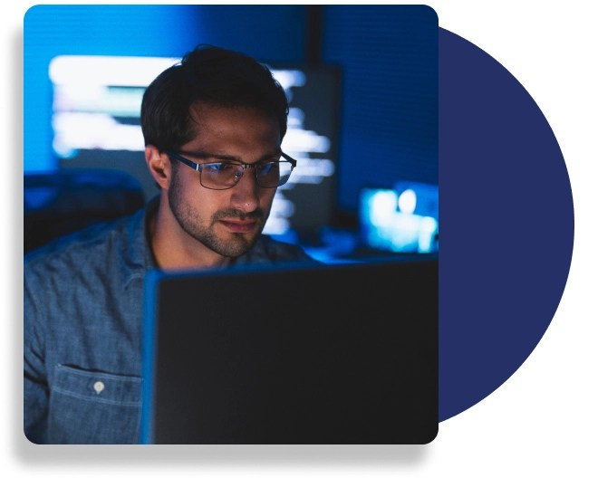 A professional wearing glasses, dressed in a blouse, working on a laptop.