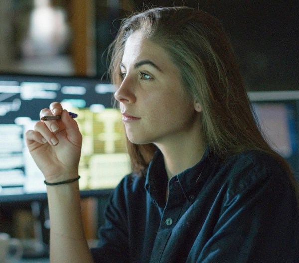 An individual sitting in front a computer, with a computer behind them.