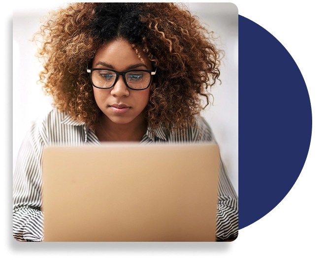 An individual wearing glasses, types on a laptop.