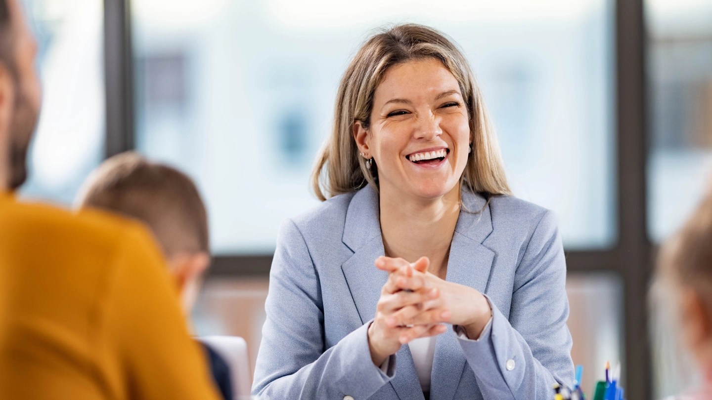 A smartly dressed professional sitting at a desk talking to a family with two young children.