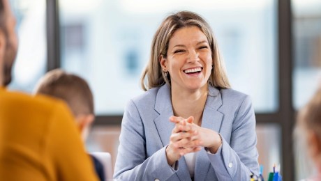 A smartly dressed professional sitting at a desk talking to a family with two young children.