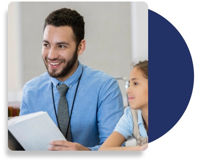 A smartly dressed teacher and a young student sitting at a desk.