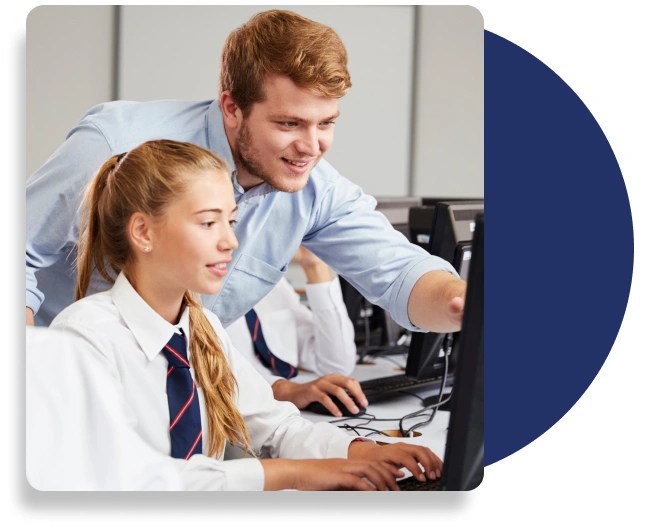 A teacher learning down to assist a student with something on their computer.