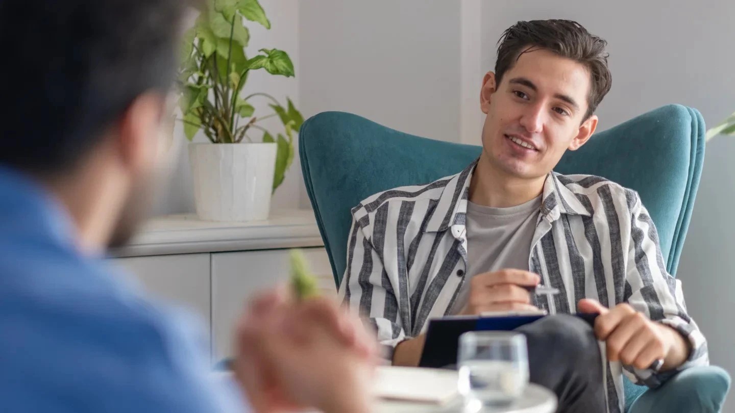 A psychologist listens to a patient and takes notes.